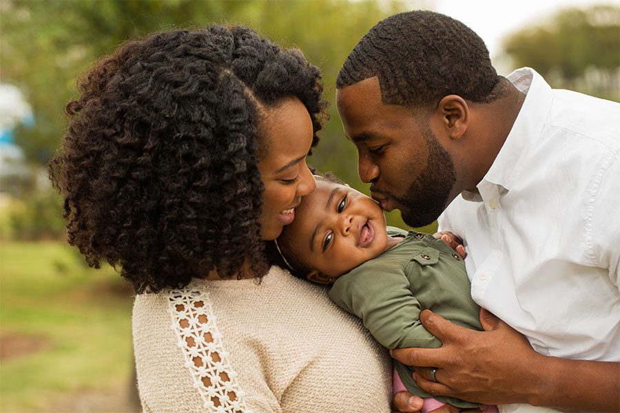 Personal Insurance - Young Parents Holding And Playing With Their Baby Outside